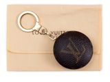 louis vuitt key chain with a black ball on a beige pouch
