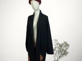 un mannequin vêtu d'un manteau noir et d'un chapeau rouge