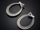 a pair of silver hoop earrings on a black surface