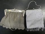 two silver purses sitting on top of a table next to each other