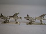 pair of silver plated fish figurines sitting on a white surface