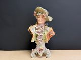 une figurine représentant une femme portant un chapeau et tenant un sac à main