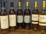 six bottles of wine are lined up on a wooden table