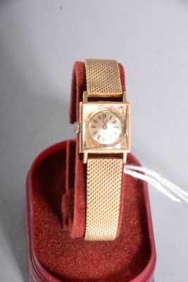 a gold watch sitting in a red box on a table