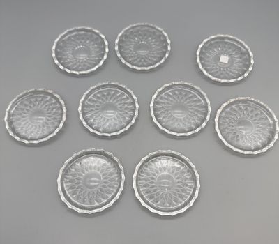 six clear glass plates on a gray surface with a white background