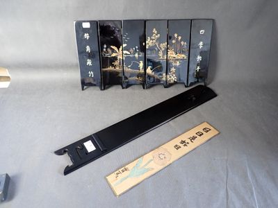 un paravent oriental noir et doré et une règle posés sur une table