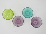 four different colored glass bowls sitting on top of a white surface