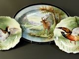 three plates with birds painted on them sitting on a table