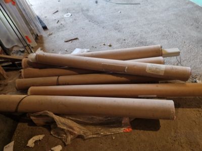 un tas de tuyaux en carton posé par terre à côté d'un radiateur