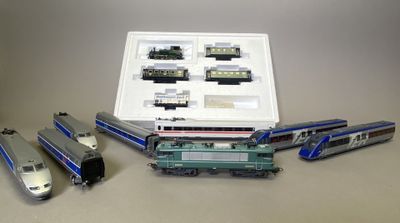 Plusieurs trains miniatures sont posés sur une table, à côté d'une boîte blanche.