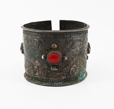 un gros plan sur un bracelet en métal orné d'une pierre rouge au centre