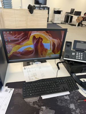 un bureau sur lequel se trouvent un écran d'ordinateur, un clavier et un téléphone