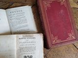 two old books on a wooden table with one open and the other closed