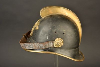 un vieux casque posé sur un support, sur fond noir