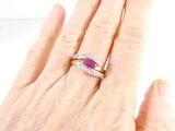 woman ' s hand holding a ring with a purple stone on it