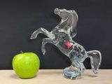 a glass figurine of a horse and an apple on a table