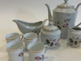 several cups and a teapot are sitting on a white table