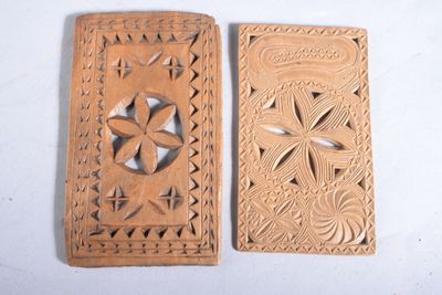 paire de plaques en bois sculptées représentant des fleurs et des feuilles sur fond blanc