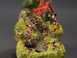 two figurines of a small house on a rock