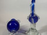 two blue glass figurines sitting next to each other on a white surface