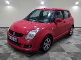 La Suzuki Swift rouge est garée dans une grande pièce.