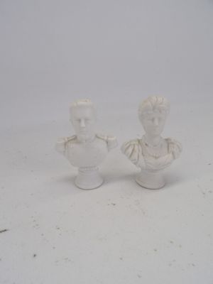 une paire de busturines blanches représentant un homme et une femme, posées sur une surface blanche