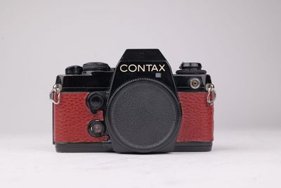 L'appareil photo est rouge et noir, avec un objectif noir.