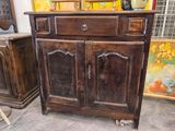 a wooden cabinet with two doors and a vase on top of it
