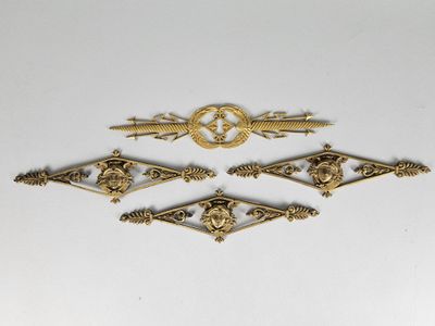 four antique brass plated metal ornaments on a white surface