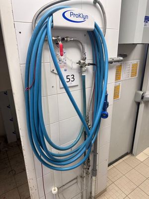 a blue hose attached to a wall in a public restroom