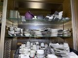 many plates and bowls on the shelves in the kitchen