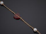 a gold bracelet with pearls and a red stone