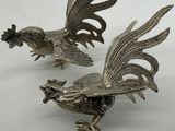 pair of silver plated rooster figurines on white background