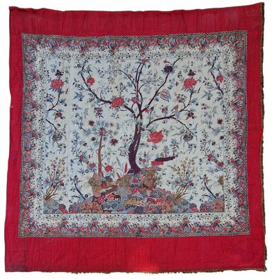 une couette rouge et blanche ornée d'un arbre et de fleurs