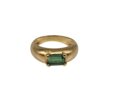 un gros plan d'une bague en or sertie d'une tourmaline verte