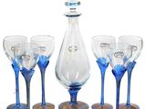 four wine glasses and a decanter set on the table