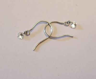 boucles d'oreilles plaquées argent ornées de cristaux transparents sur un fond blanc