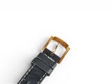 a close up of a watch on a white surface with a gold buckle