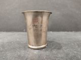 an old silver cup with a handle sitting on top of a table