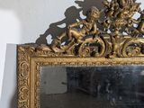 a mirror that has a gold frame with a picture of angels on it