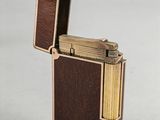 a gold plated lighter with a wooden case on a white surface