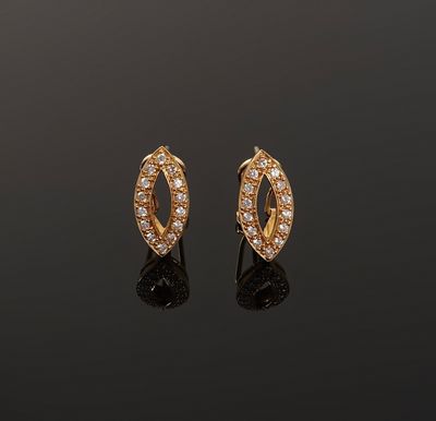 a pair of gold and diamond earrings on a black surface