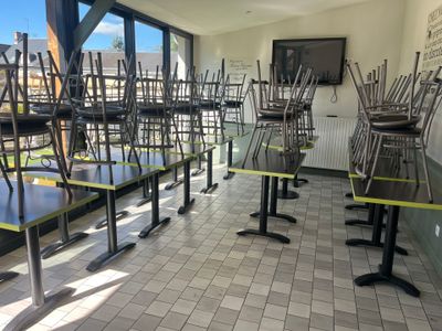 Des tables et des chaises sont alignées dans une pièce dotée d'une grande fenêtre.