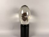 a small glass ball with a black base on a white surface