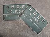 deux plaques d'immatriculation vertes posées sur une surface en béton