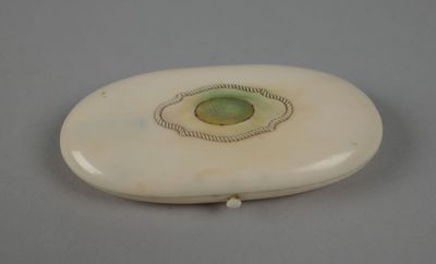une image représentant un objet ovale blanc avec une pierre verte au centre