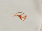 a white plate with an orange bird on it