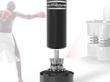 a black punching bag on a stand with a man in the background