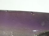 a purple bowl sitting on top of a table next to a white wall