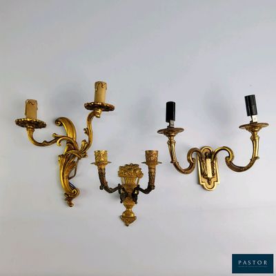 three brass wall sconces mounted on a white wall